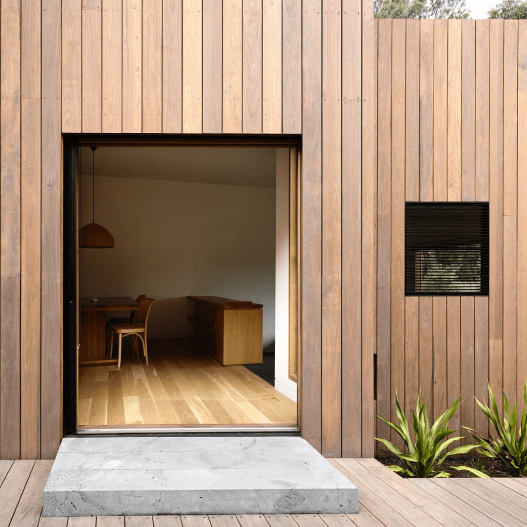 Vertical timber cladding framing an entrance to an open living space